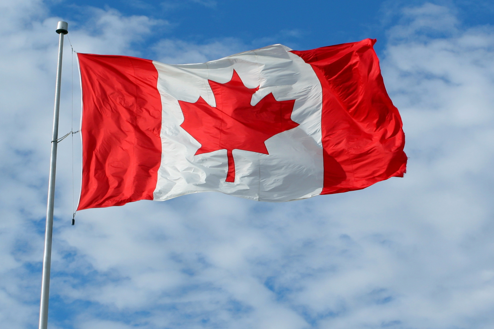 Bandera de Canadá con dos franjas rojas verticales y una hoja de arce roja en el centro.