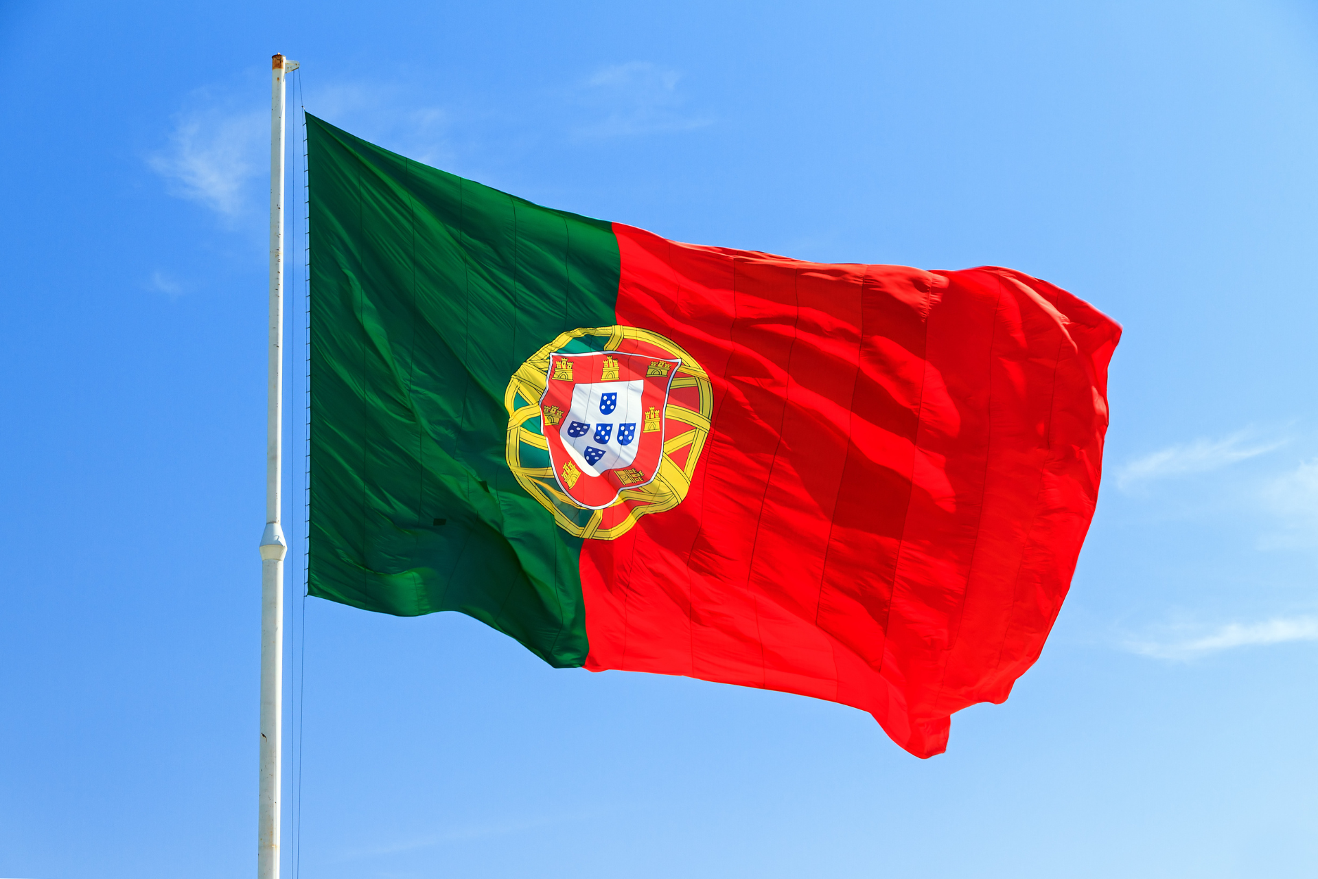 Bandera de Portugal con una franja vertical verde, un escudo de armas en el centro, y una franja roja a la derecha.